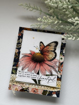 Card with a soft daisy and butterfly over floral paper: 'We are all a mess, but it is how we keep it together that makes us beautiful.'