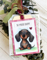 Tag-topped card with the dachshund puppy colored black-and-tan, stamped 'so much happy.'