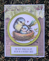 Purple-toned card with the mama bird and chick nested in a green circle frame over a pressed-flower background and the sentiment 'The best things in life begin in a mother's nest.'