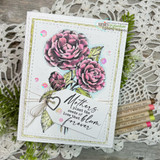 White stitched card on lace, camellia blooms coloured in plum and rose with green leaves, twine and a heart charm, sentiment 'Mothers plant the seeds of love that bloom forever'.