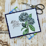 Navy-matted card on birch wood, camellias coloured in soft teal and blue with green leaves, sentiment 'Mothers plant the seeds of love that bloom forever'.