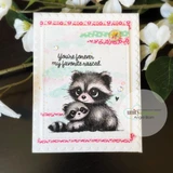 The raccoon and baby on a soft floral card, captioned 'You're forever my favorite rascal.'