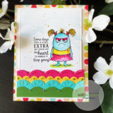 White card with a grumpy pink monster above a scalloped rainbow border and 'Some days feel a little EXTRA'.