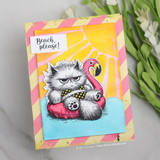 Card sample — a grumpy fluffy Pissy Kitty in a pink flamingo pool float, 'Beach, please!', on sunny striped paper.