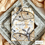 The moth on a distressed tag in a rustic frame — 'Let your light lead.'