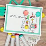 Card of two party chickens with balloons and cake, "You're still younger than you'll be next year!"