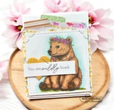 Sample card with the bear cub colored brown on a sunflower print panel with a yellow heart and a sentiment strip reading 'You are wildly loved'.