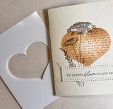 Handmade card using the Heart of the Matter stencil to mask a kraft heart filled with a stamped dandelion and script, finished with 'Let yourself bloom in your own time', beside the cut white stencil.