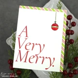 Sample card using the pack: a clean white panel with a large red script a very merry sentiment and a single striped ornament hanging above it, edged in a candy-stripe border.