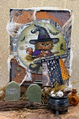 Spooky mixed-media card with the witch cat over a graveyard scene and 'drop a house on them.'