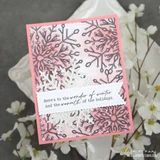 Frosted Lace card from Unity Stamp Co: navy lace snowflakes stamped across a blush pink panel with white glittered snowflake accents and a stitched banner reading 'Here's to the wonder of winter and the warmth of the holidays.'