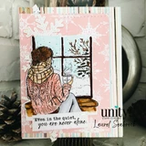 Card using Sugarplum Frost papers, a woman in a knit sweater sitting by a frosted window with a mug, layered on pink and mint snowflake sheets.