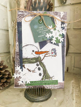 Card with the snowman and bird over vintage papers with a snowflake tag and the warm-hugs sentiment.