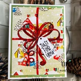 Handmade sample card using the I'll Be Home for Christmas papers — a large red ribbon bow and a gift tag over a collage of homespun holiday patterned papers.