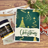 Deep green Christmas card with gold foiled stencil trees, dotted garlands and stars, a torn cream strip and a green Merry Christmas sentiment.