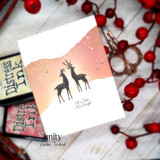 A white card with the two deer in solid black silhouette on a coral and cream horizon, with a small strip reading 'All is Calm, All is Bright.'