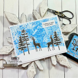 A bright blue distressed card with the deer and spruce silhouettes across a snowy horizon, with a small flag reading 'Wishing you peace in every season.'