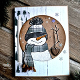 Snowman in a plaid hat and scarf in a circle over white wood with snowflakes.