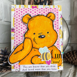 Golden bear with a tiny smiling bee against a pink heart-print background, above the words "You are braver than you think. And loved more than you know."