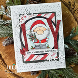 A cardmaking project featuring a chubby, cheerful cartoon Santa holding pine sprigs from Unity Stamp Co's A Little Ho Ho Ho red rubber stamp set, with the sentiment 'Ho Ho Ho'.