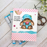 Handmade card made with Unity Stamp Co’s The Softest Thoughts red rubber stamp set — a fluffy bunny in a knit beanie hugging a heart, with a snowflake — stamped and colored, with the sentiment “Sending a big squeeze”.