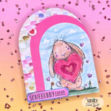 Arched card of the bunny holding a pink heart under a blue sky, 'somebunny cares.'