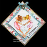Diamond shaped card with an aqua bow and heart charm on a black background, the two girls leaping into a heart shape in pink tones with the faith, hope and love verse.