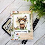 A cardmaking project featuring a shaggy Highland cow with a little bird perched on its head, in a wildflower meadow from Unity Stamp Co's Seen & Herd red rubber stamp set, with the sentiment 'Oops... it's pasture your birthday'.