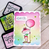 Card of the frog with a pink balloon over rainbow ink with "Love you more than lily pads & sunshine."