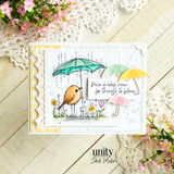 Card with the bird under an umbrella over soft papers with a second yellow umbrella and 'Rain makes room for things to bloom.'