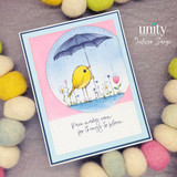Card with the bird under a purple umbrella on a pink-and-blue circle and 'Rain makes room for things to bloom.'