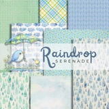 Cover of the Raindrop Serenade 6x6 paper pack, gentle blue rain-themed papers with an umbrella, a bluebird, raindrops and plaid, labeled 'Raindrop Serenade'.