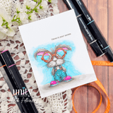 A cardmaking project featuring a nerdy bunny in big round glasses and denim overalls, surrounded by books from Unity Stamp Co's Clever Cottontail red rubber stamp set, with the sentiment 'Hope your birthday is one for the books.'.