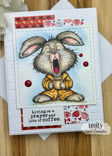 Card with the yawning bunny in a yellow robe over coffee papers and 'Living on a prayer and lots of coffee.'
