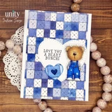 Sample card built from the pack: a blue quilt-block patchwork panel with a stamped teddy bear in overalls, a stitched blue heart, and a circle sentiment reading LOVE YOU A BEARY BUNCH.