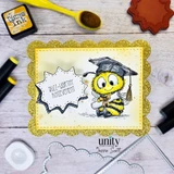 Handmade card featuring a cute bumblebee wearing a graduation cap and holding a diploma, framed with a glittery scalloped border, with the sentiment “Buzz-worthy achievement,” surrounded by crafting tools and supplies.