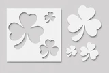 Lucky 3 stencil, a white panel cut with shamrocks in four sizes, two solid and two open outlines, on a grey background.