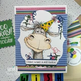 Festive card with the donkey amid streamers and 'Older, wiser, & still kickin'.'