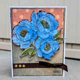 Handmade card with layered blue flowers, vintage patterned background, and brown ribbon accent.