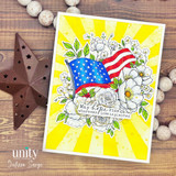 Patriotic floral card with an American flag, white flowers, yellow sunburst background, and the sentiment, “May hope rise wherever love is planted.”