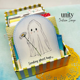 Pocket card with a ghost holding a daisy and the sentiment “Sending ghost hugs,” displayed in a striped organizer box.