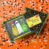 Halloween card on an orange sequin background with the three costumed chickens - mummy, ghost and Frankenstein - colored bright, beside a 'Fowl things are happening' banner.
