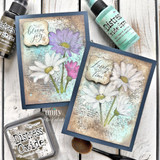 Two vintage-style daisy cards with distressed backgrounds and uplifting floral sentiments displayed alongside Distress crafting supplies.