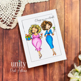 Card with two glamorous women holding cocktails and a gift, stamped 'Classy with a touch of trouble.'