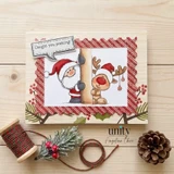 A card in a red plaid frame with the Santa hatted bear peeking around a wooden post beside the reindeer with ornaments on his antlers, colored in warm reds and browns, with a speech bubble reading 'Caught you peeking!'