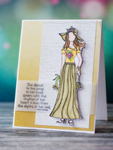 Kraft and white card with a girl in a soft green skirt on a gold panel, stamped with the verse 'She dances to the songs in her head, speaks with the rhythm of her heart, & loves from the depths of her soul'.