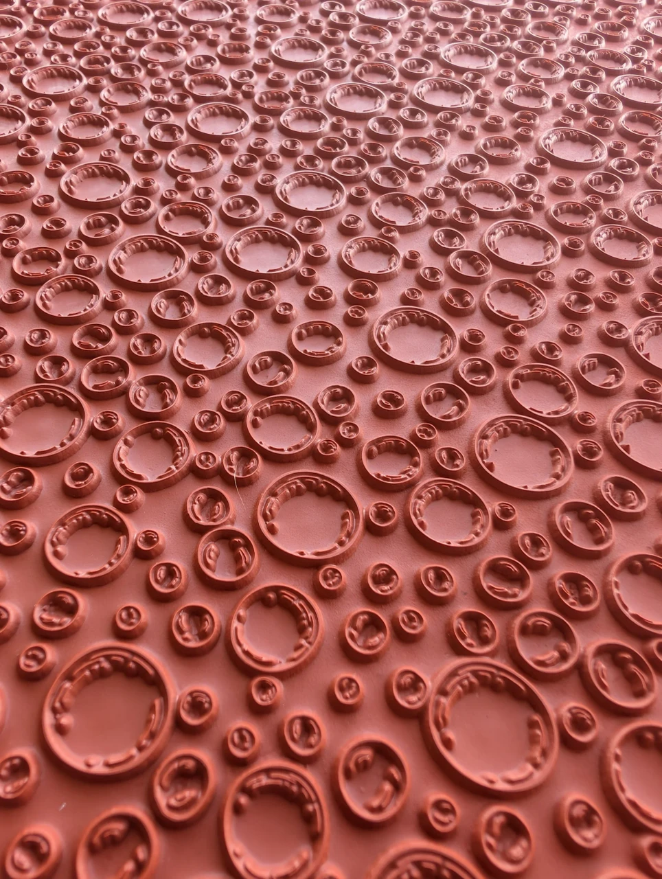 Close view of varied raised bubble rings on a red rubber pottery texture mat.
