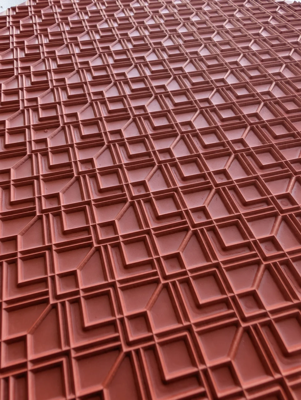 Close view across nested raised diamond shapes on a red rubber pottery texture mat.