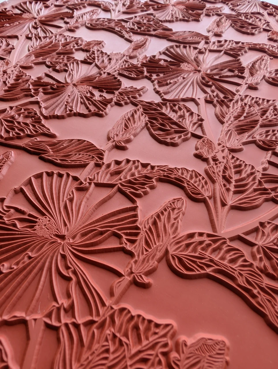 Close view of raised flower petals, centers, and veined leaves on the red rubber Tropical Bloom texture mat.