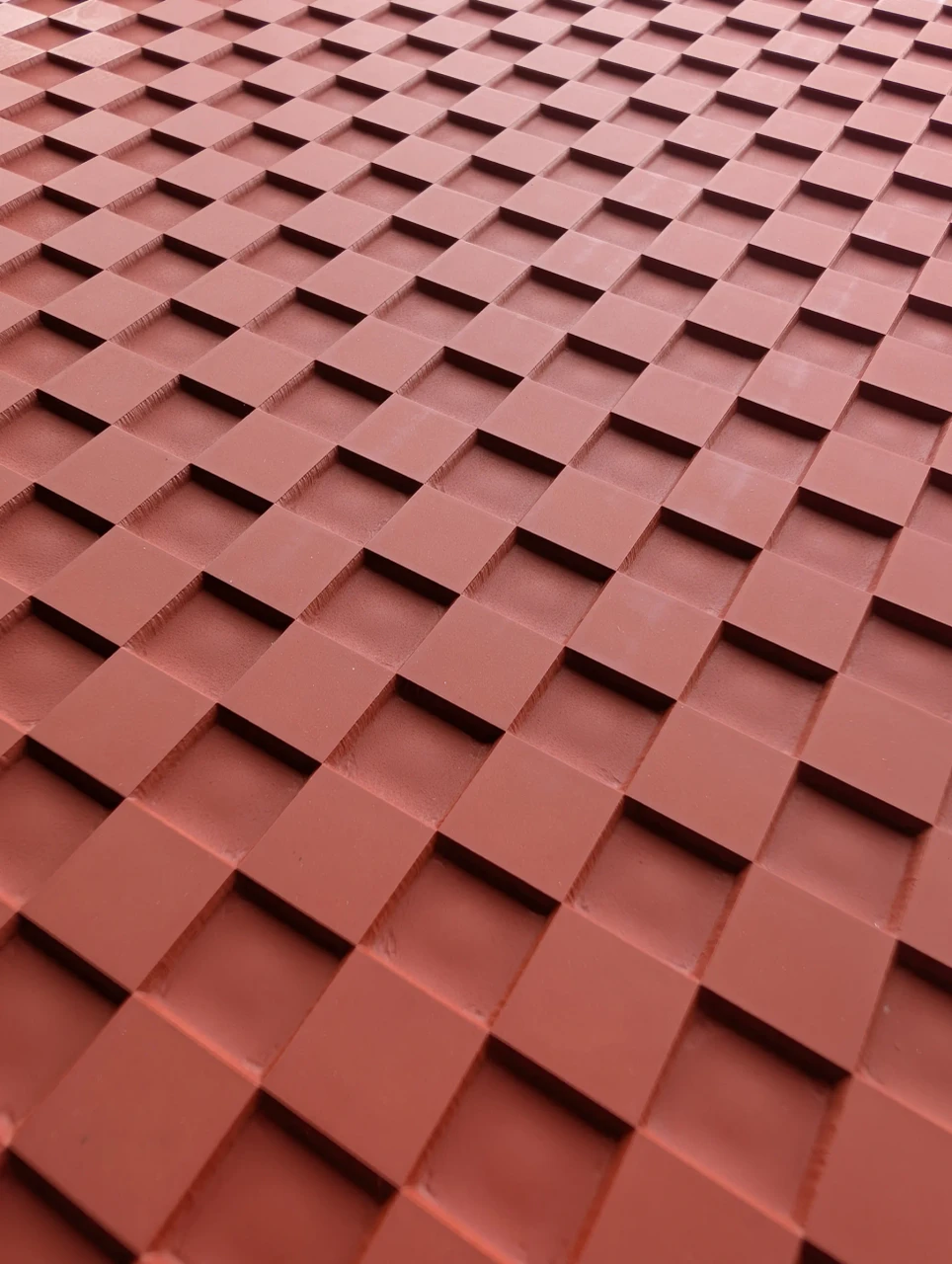 Angled close view of alternating raised square bands creating a basketweave effect on a red rubber texture mat.